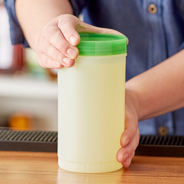 A person holding a Choice plastic container with a green lid.