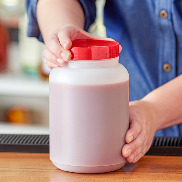 A person holding a Choice 2 Qt. jar of red liquid.