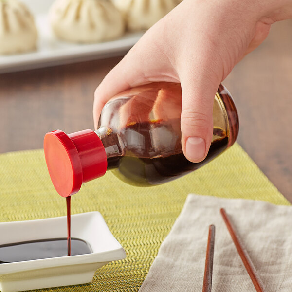Soy sauce being poured out of a soy sauce bottle into a sauce dish