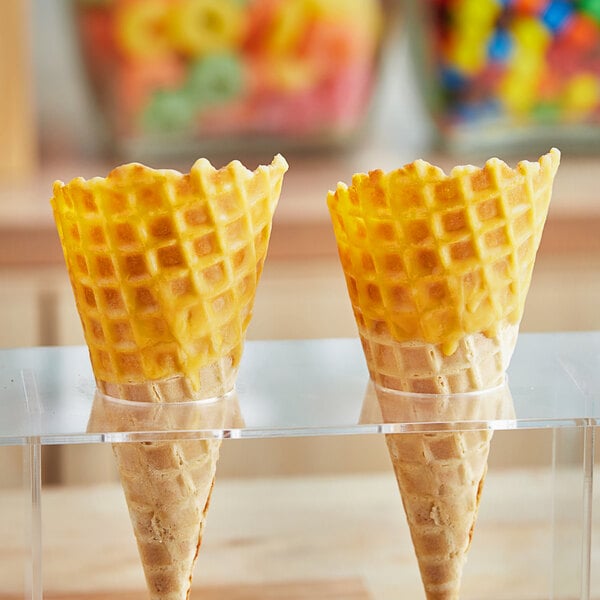 A yellow waffle cone with J. Hungerford Smith Butterscotch Cone Shell Coating on top of ice cream.