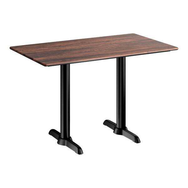 A rectangular standard height table with a textured walnut finish top and two black metal end base plates.