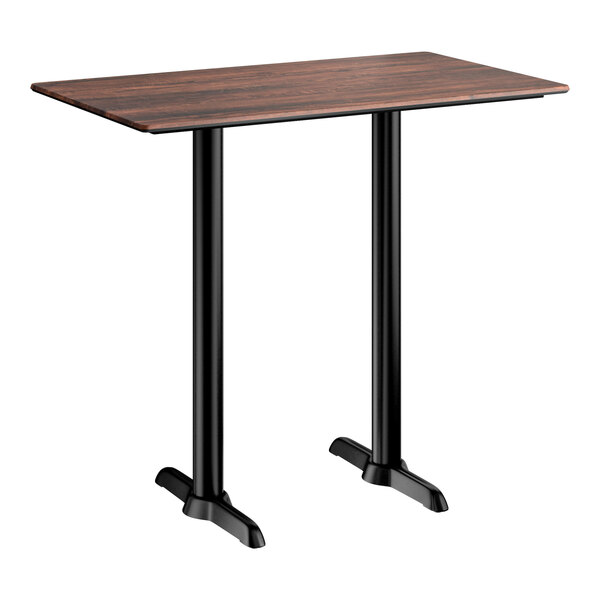 A rectangular bar height table with a textured walnut finish top and two black metal end base plates.