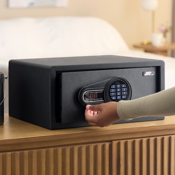 A black steel hotel safe with an electronic keypad lock placed on a wooden surface.