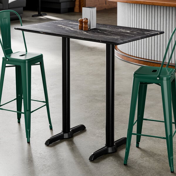 A rectangular bar height table with a smooth dark finish and two sturdy black base plates.