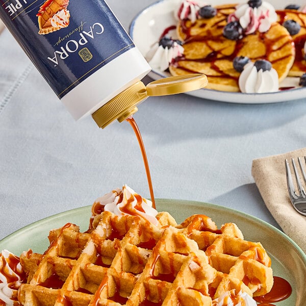 A person pouring Capora Pumpkin Pie flavoring sauce onto a waffle.