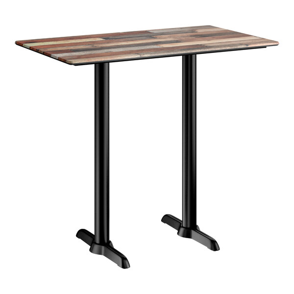 A rectangular bar height table with a textured mixed plank finish top and two black metal end base plates.