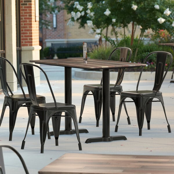 A Lancaster Table & Seating Excalibur rectangular dining table with a textured wood finish and outdoor base plates on a patio.