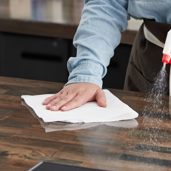 A person spraying a surface with WypAll industrial wipers.