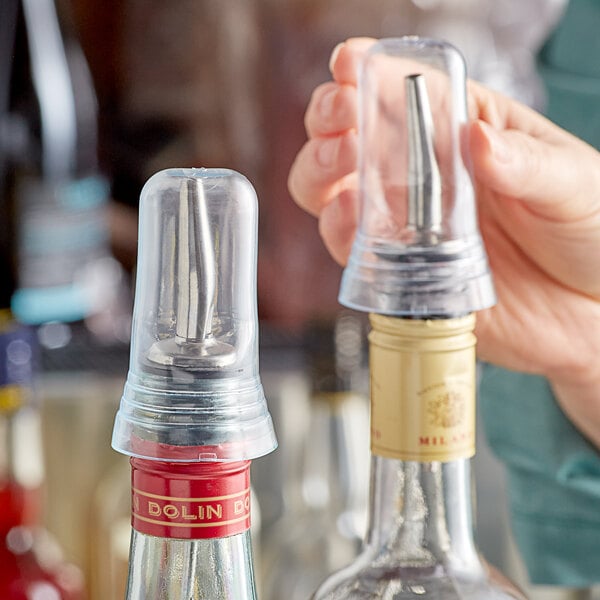 A hand using a Tablecraft translucent liquor pourer cover on a bottle of liquor.