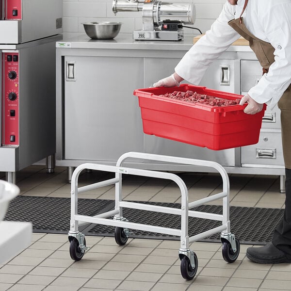 A man in a kitchen holding a red Regency meat tote container.