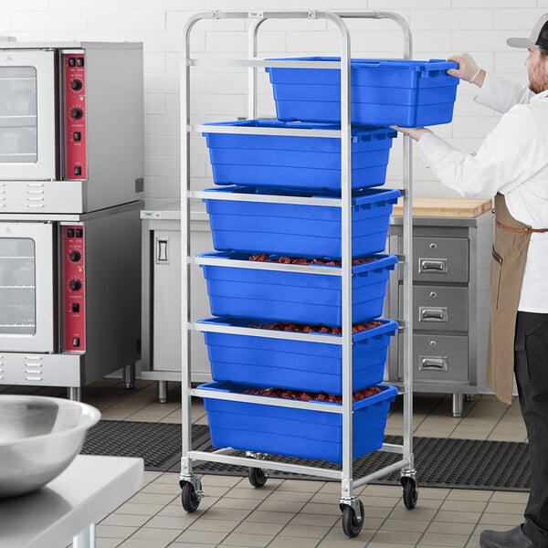 A man in a kitchen holding blue plastic containers on a white Regency aluminum lug rack.