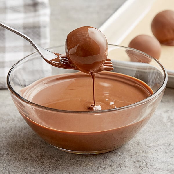 Bonbon being dipped in melted chocolate