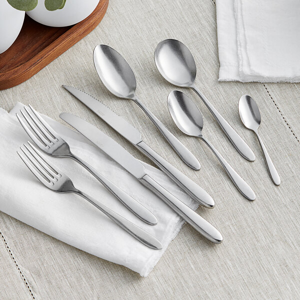 A close-up of an Acopa Pangea dinner knife and spoon on a table.