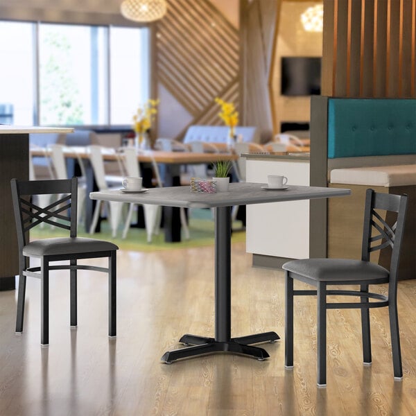 A Lancaster Table & Seating rectangular reversible white and gray slate laminated table top on a table in a restaurant dining area with a cup on it.