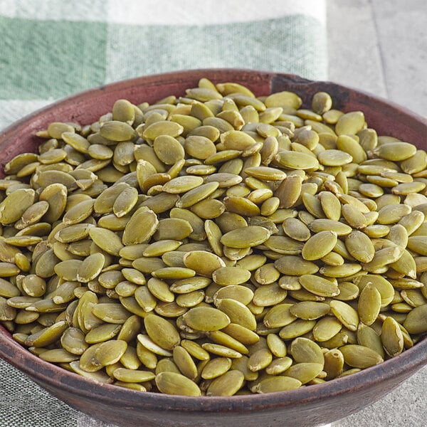 A bowl of Regal Raw pumpkin seeds on a table.