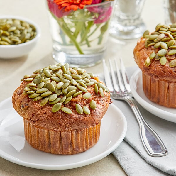 A muffin with pumpkin seeds on top on a plate.