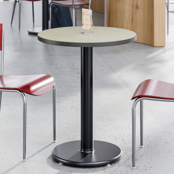 A round table with a reversible white or gray slate laminated top and a black pedestal base.