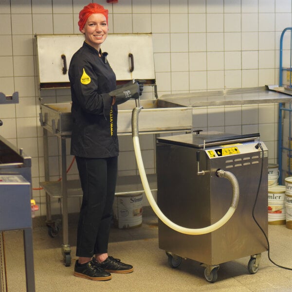 A woman wearing a black uniform using a VITO fryer oil filter system in a school kitchen.