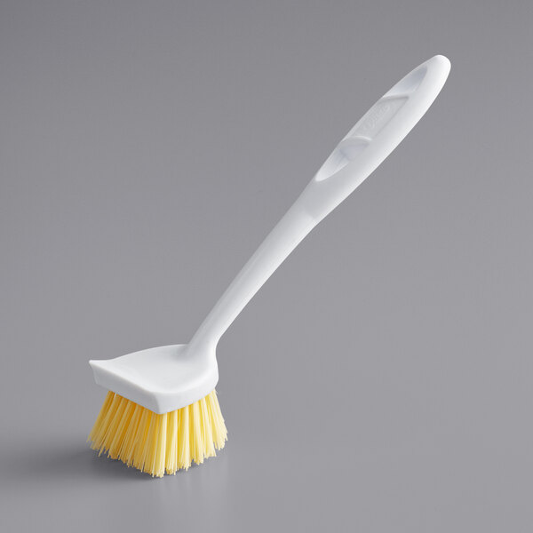 A Quickie vegetable brush with white bristles and a yellow tip.