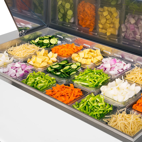 A Turbo Air refrigerated prep table with trays of cut vegetables.
