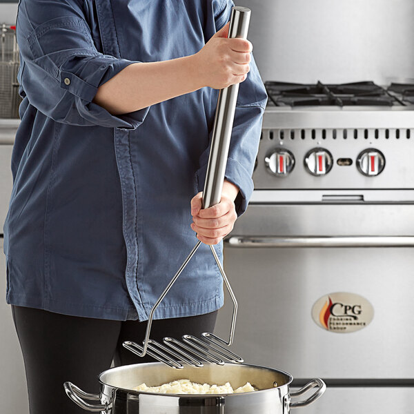 A person using a Tablecraft stainless steel potato masher over a pot of food.