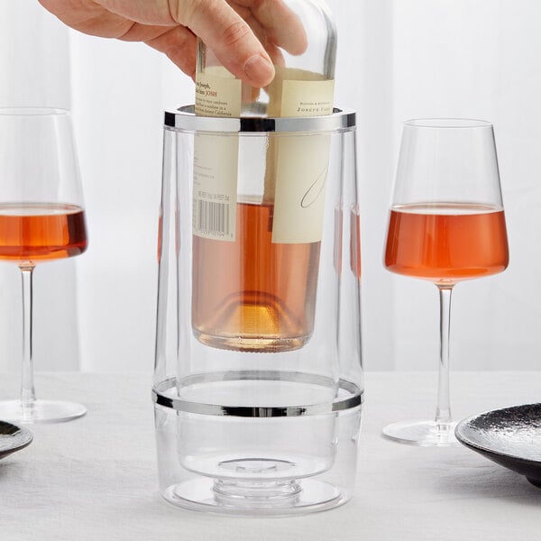 A hand putting a wine bottle into a clear Choice acrylic wine cooler.