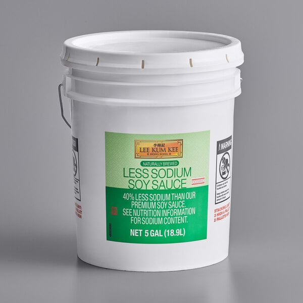 A white bucket with a green and white label for Lee Kum Kee Less Sodium Soy Sauce.