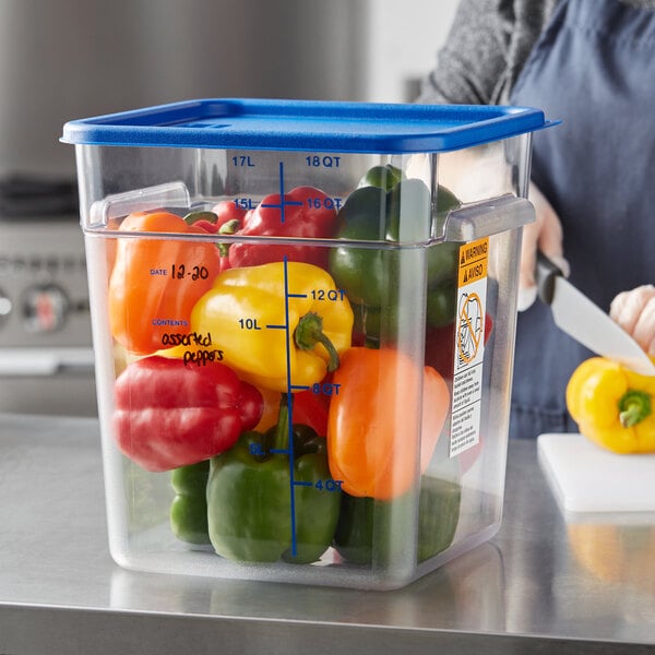 A woman cutting yellow and red bell peppers in a Vigor clear food storage container on a kitchen counter.