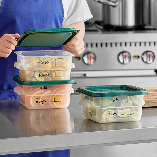 A woman in an apron holding a Vigor translucent polypropylene food storage container filled with food.
