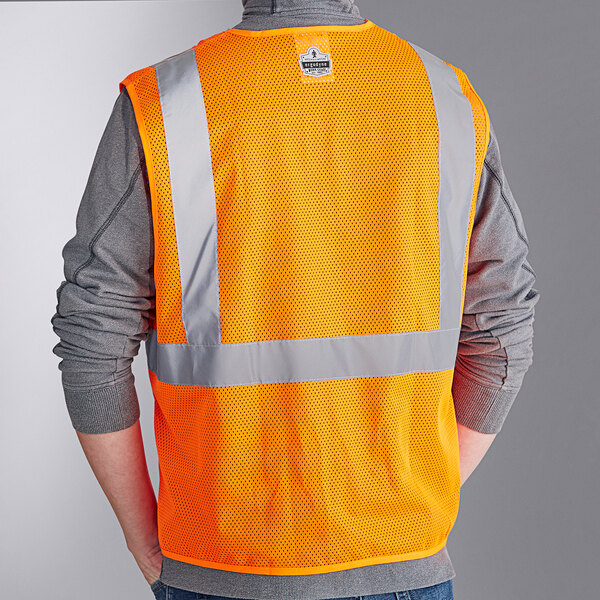 A person wearing an orange Ergodyne reflective mesh vest.