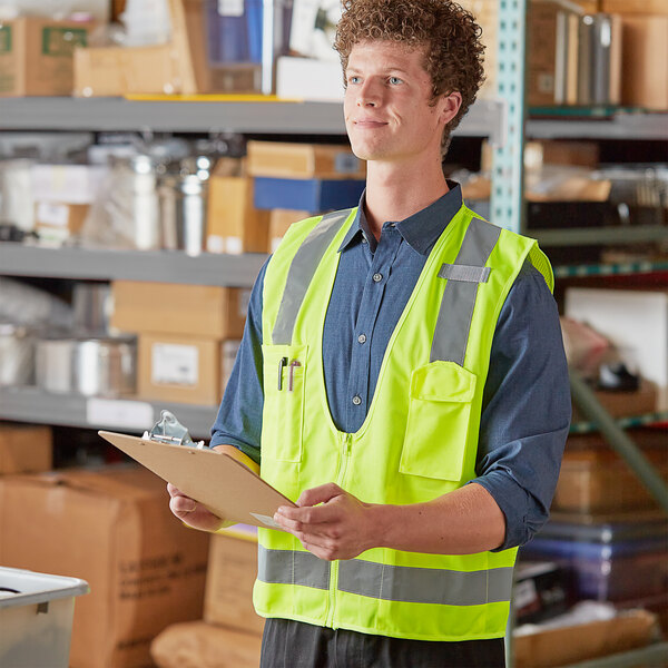 A man wearing a lime green Ergodyne safety vest holding a clipboard.