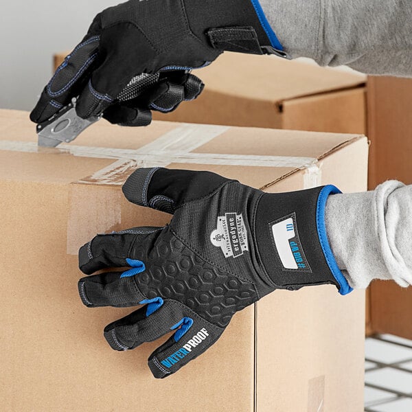 A person wearing Ergodyne ProFlex 818WP black thermal waterproof work gloves holding a box.