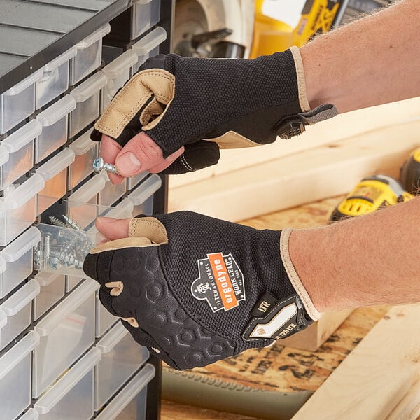 A man holding a pair of Ergodyne heavy-duty leather-reinforced framing gloves in a drawer.