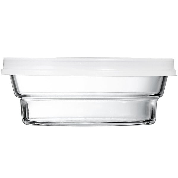 A clear glass Arcoroc container with a white lid.