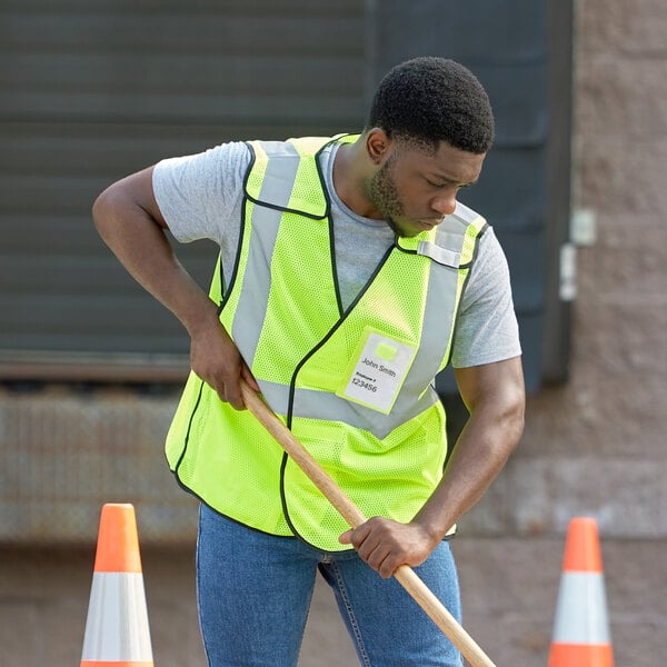 A man in a lime Ergodyne safety vest shoveling.