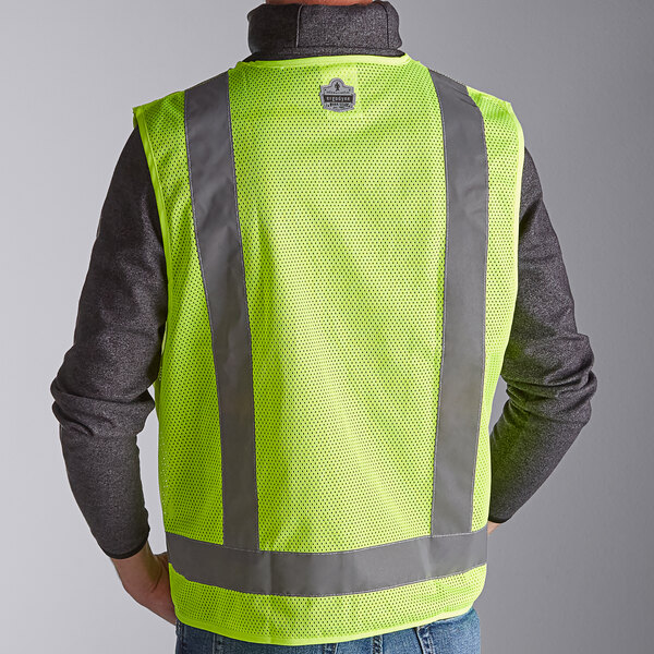 A person wearing a lime yellow Ergodyne surveyor vest with reflective stripes.