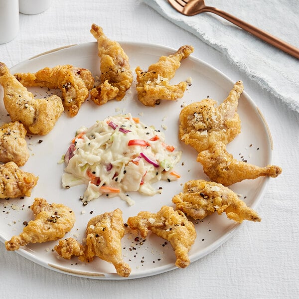 A plate of Manchester Farms partially boned quail legs with coleslaw and pickles.