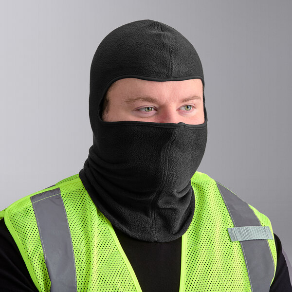 A man wearing a black Ergodyne N-Ferno fleece balaclava and yellow safety vest.