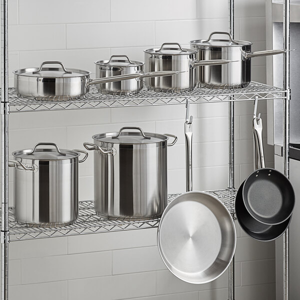 A Vollrath stainless steel rack with Optio cookware set pots and pans.