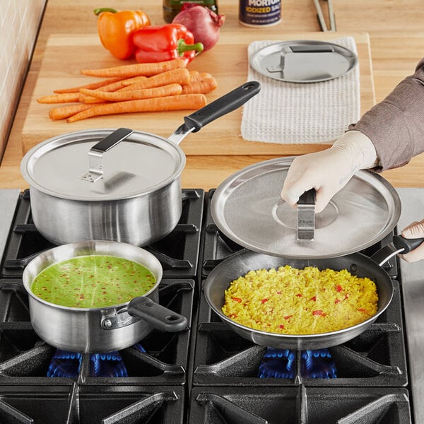 A person cooking food on a stove using Vollrath stainless steel cookware.