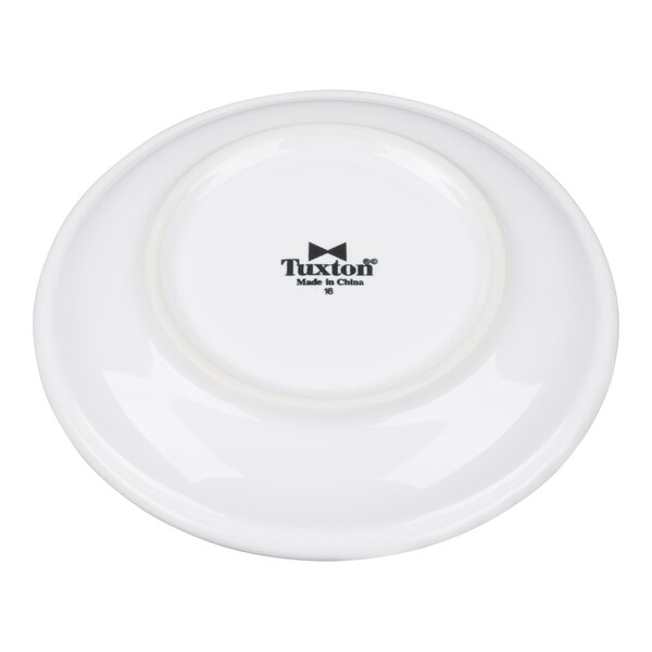 A white china cappuccino saucer with the Tuxton logo on the bottom.