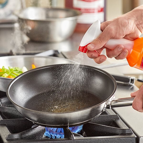 A person spraying Vegalene liquid release into a pan.