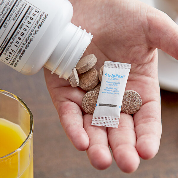 A hand holding a small packet of Multisorb StripPax.