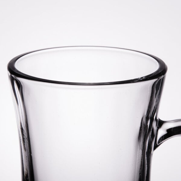A close up of a Libbey clear glass coffee mug with a handle.