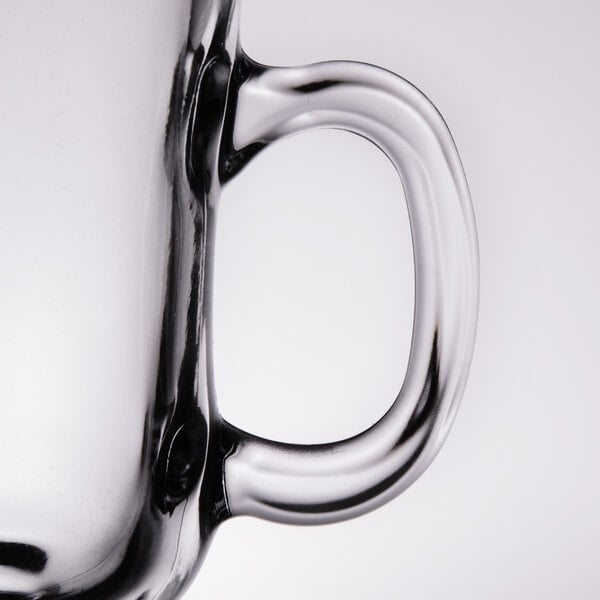 A close up of a Libbey clear glass coffee mug with a handle.