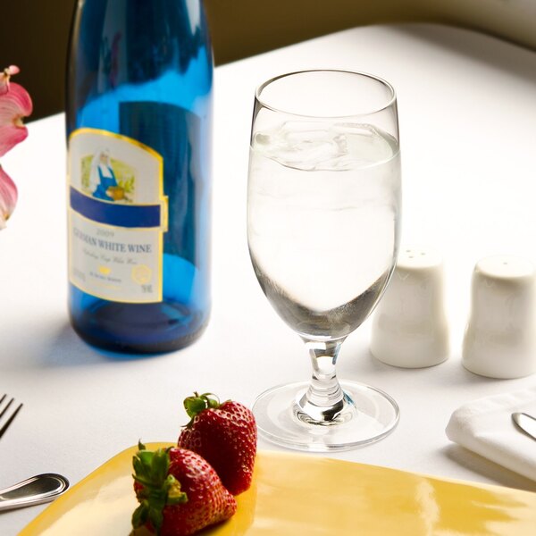 A Stolzle Nadine goblet filled with water on a table with a plate of strawberries.