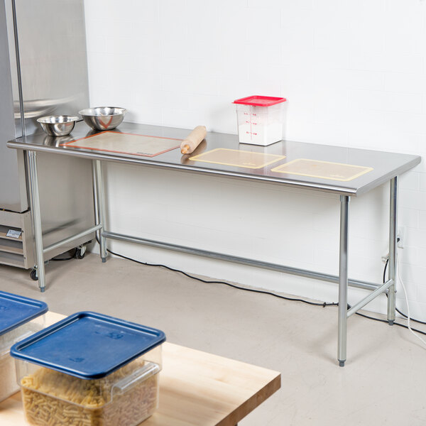 An Advance Tabco stainless steel work table with bowls on it.