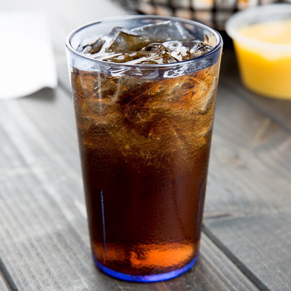 A Cambro slate blue plastic tumbler filled with brown liquid and ice with a straw.