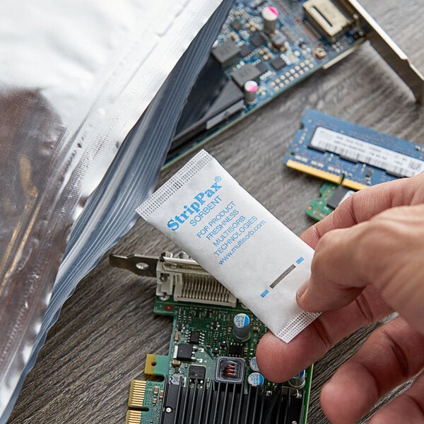 A hand holding a Multisorb StripPax desiccant packet.