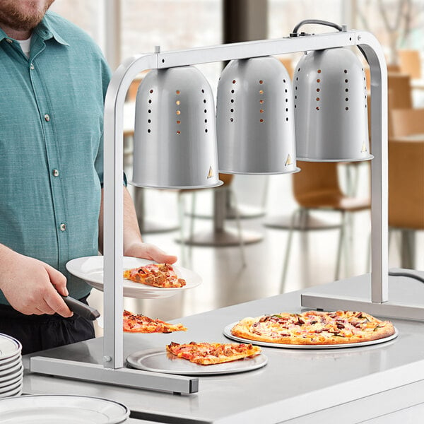 A man serving pizza from a ServIt pass through heat lamp over a hotel buffet counter.